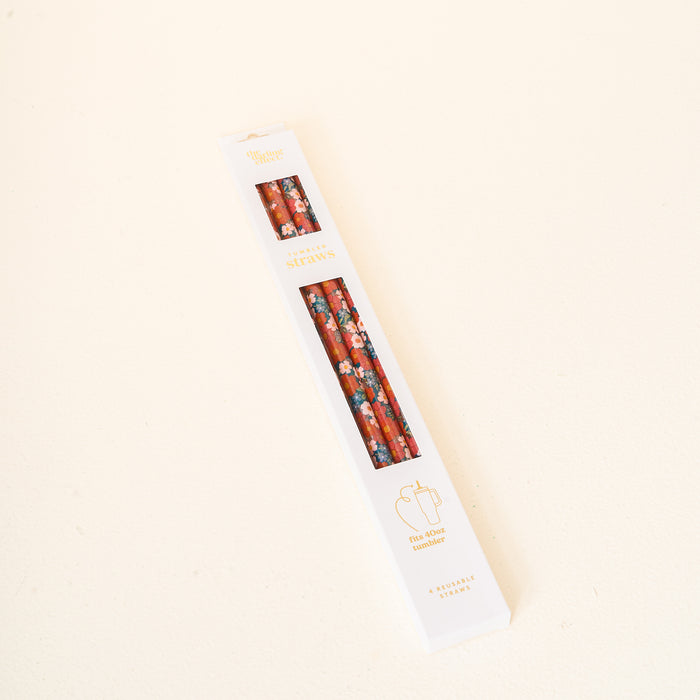 A white rectangular box from The Darling Effect, containing the Wild About You Teal 40 oz Tumbler Straw Set with a red floral pencil straw design, rests on a light, off-white surface. The packaging is adorned with gold and black text as well as a small logo near the bottom, making these reusable straws ideal for your 40 oz tumbler.