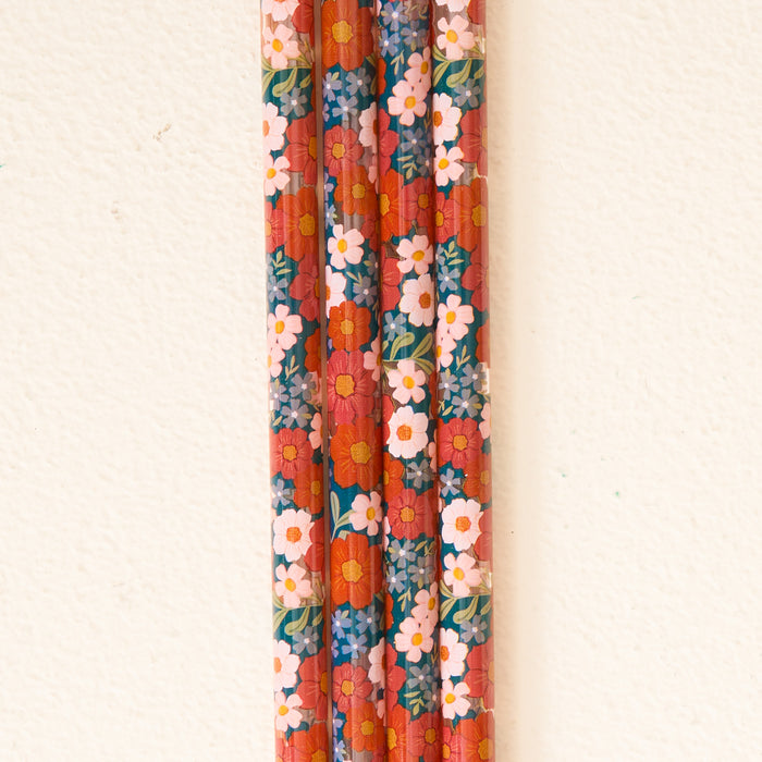 Vertical rows of pencils featuring a bold red background and a vibrant floral pattern with orange, white, and pink blooms resemble The Darling Effect’s Wild About You Teal 40 oz Tumbler Straw Set—designed to pair seamlessly with your 40 oz tumbler or other reusable straws for an extra pop of style.