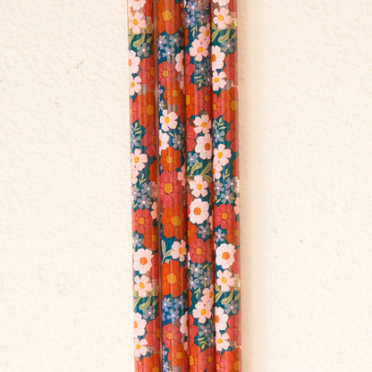 Vertical rows of pencils featuring a bold red background and a vibrant floral pattern with orange, white, and pink blooms resemble The Darling Effect’s Wild About You Teal 40 oz Tumbler Straw Set—designed to pair seamlessly with your 40 oz tumbler or other reusable straws for an extra pop of style.