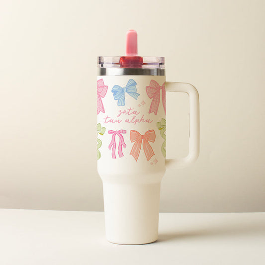 The Darling Effect's Zeta Tau Alpha 40 oz Lifestyle Flip Straw Tumbler Bow Affair features a handle, colorful bows, "zeta tau alpha" in pink script, a leak-resistant flip straw lid, and a bright pink straw.