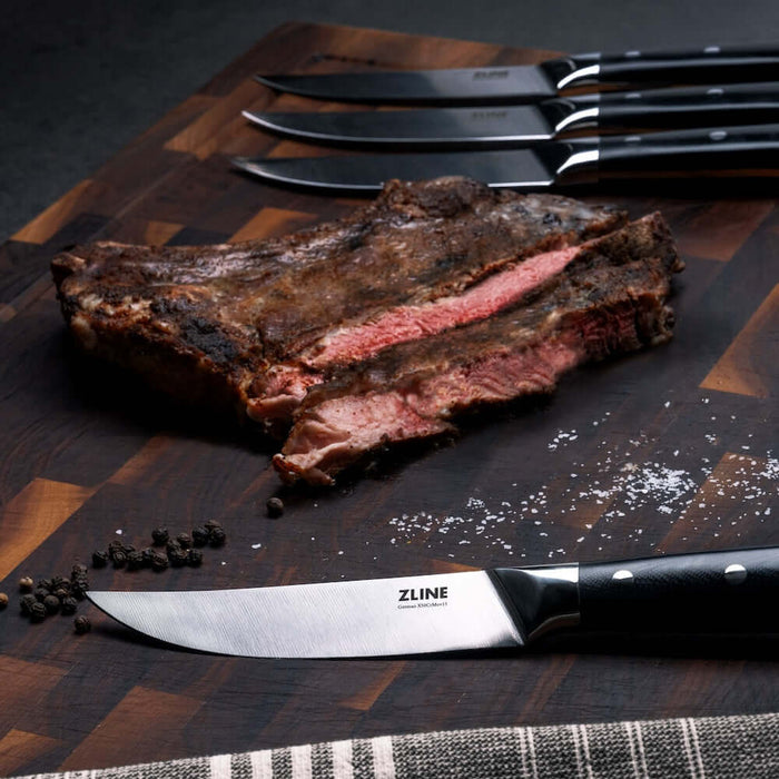 ZLINE 4-Piece Professional German Steel Steak Knife Set (STK-GS-4) on a cutting board with steak.